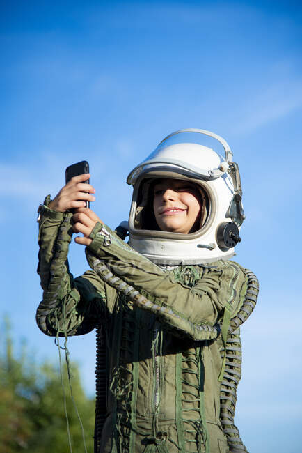 Niño vistiendo un traje espacial y tomando una selfie - foto de stock