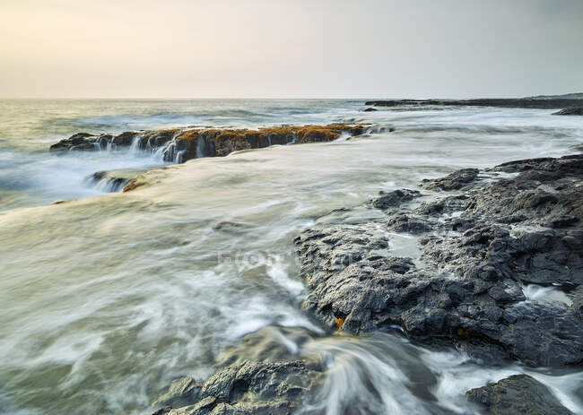 Waves splashing on volcanic rocks in Kealakekua Bay against sky during sunset — Stock Photo