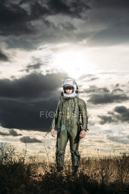 Mann posiert als Astronaut verkleidet auf einer Wiese mit dramatischen Wolken im Hintergrund — Stockfoto