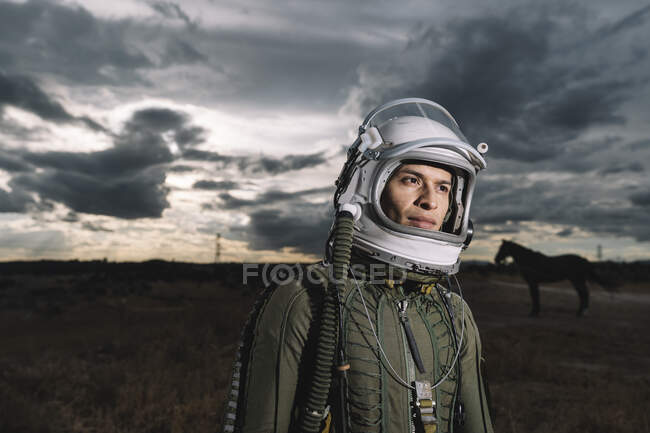 Man posing dressed as an astronaut with dramatic clouds in the background — Stock Photo