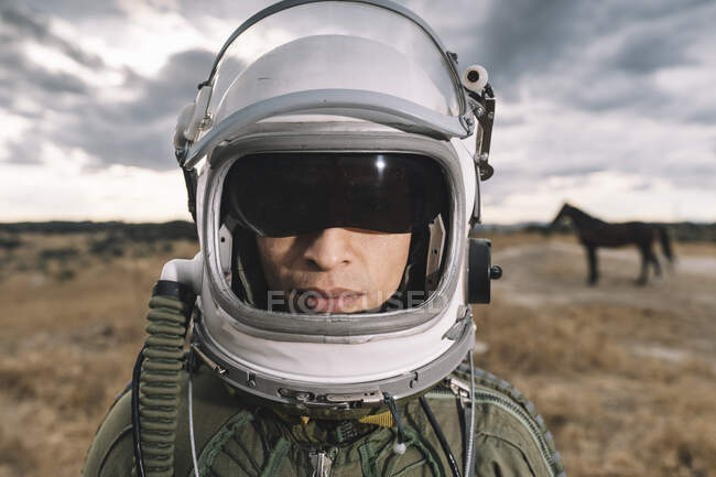 Man posing dressed as an astronaut on a meadow with dramatic clouds in the background — Stock Photo