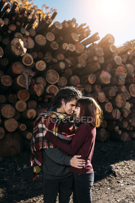 Pareja joven enamorada delante de troncos de árboles - foto de stock