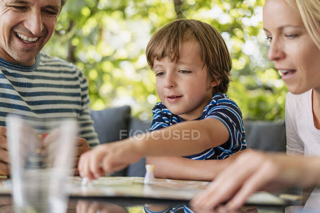 Happy parents and son playing a board game on terrace — Stock Photo
