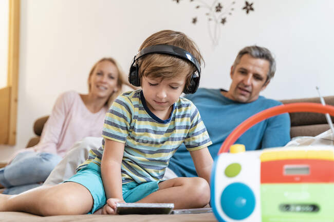 Famiglia sul divano a casa con ragazzo che ascolta musica con le cuffie — Foto stock