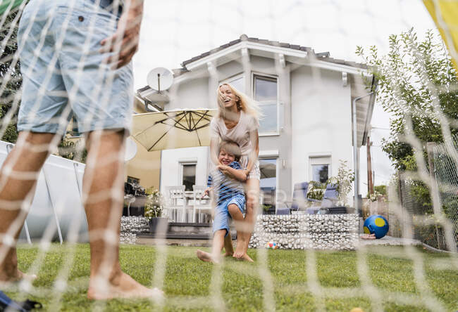 Famille heureuse jouant au football dans le jardin — Photo de stock