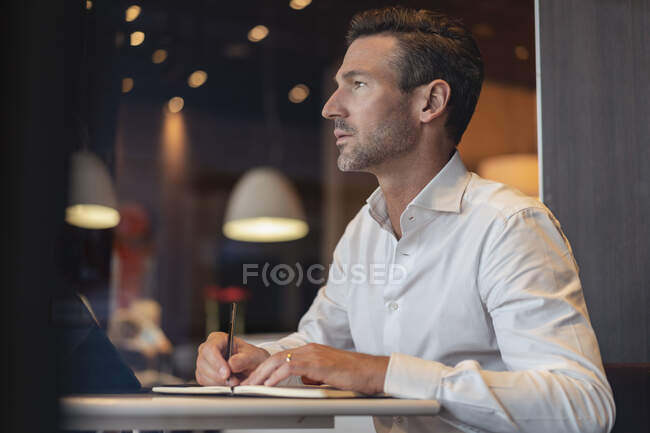 Empresario con tableta en un café tomando notas - foto de stock