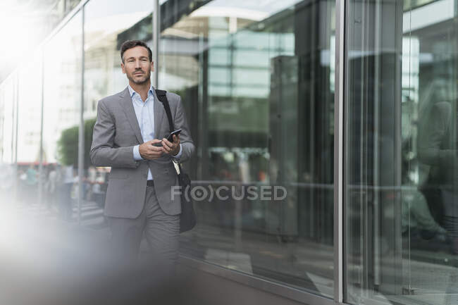Retrato de hombre de negocios con teléfono celular en movimiento - foto de stock
