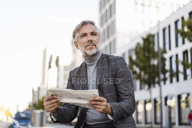 Fashionable mature businessman reading newspaper in the city — Stock Photo