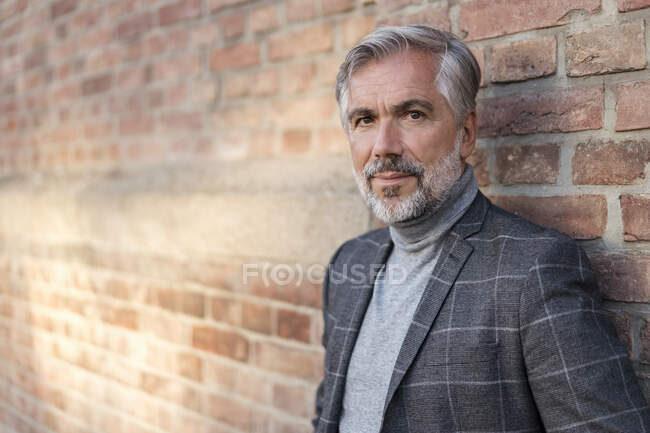 Портрет модного зрелого бизнесмена у кирпичной стены — стоковое фото