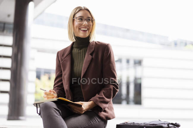 Lächelnde junge Geschäftsfrau mit Notizbuch in der Stadt — Stockfoto