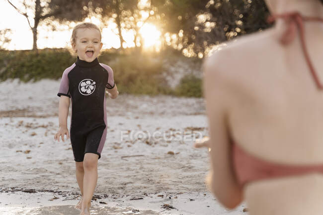 Ragazza felice con sua madre sulla spiaggia al tramonto — Foto stock