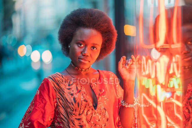 Junge Frau steht neben Neonlicht — Stockfoto