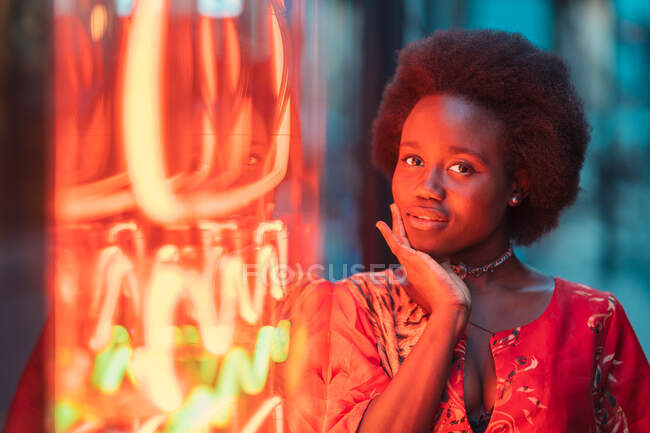 Young woman standing next to neon light — Stock Photo