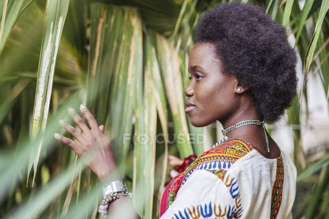 Jovem mulher de pé entre plantas tropicais — Fotografia de Stock
