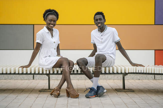 Porträt eines glücklichen jungen Paares, das draußen auf einer Bank sitzt — Stockfoto