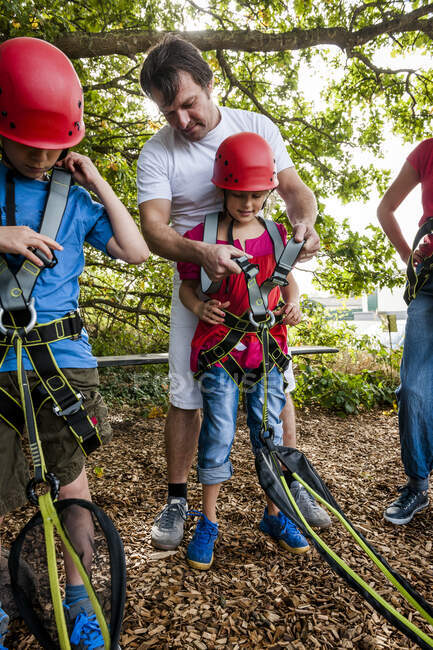 Mann hilft Mädchen bei Vorbereitungen für Hochseilgarten im Wald — Stockfoto