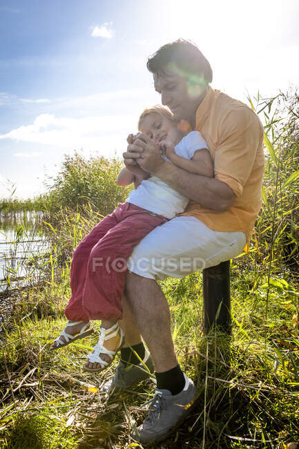 Padre e figlia seduti su un palo di legno sulla costa, Darss, Meclemburgo-Pomerania occidentale, Germania — Foto stock
