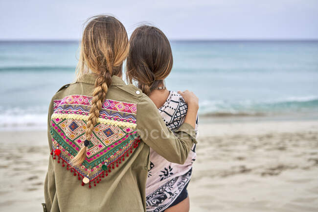 Vista posteriore di due giovani donne in piedi l'una accanto all'altra su una spiaggia — Foto stock