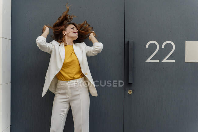 Femme d'affaires en costume pantalon blanc, debout devant la porte d'entrée — Photo de stock