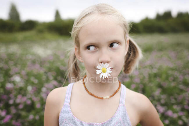 Menina com flor de camomila na boca — Fotografia de Stock