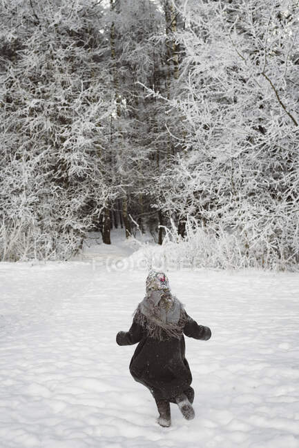 Visão traseira da menina correndo no campo de neve — Fotografia de Stock
