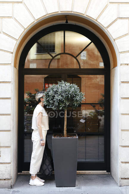 Mulher escondendo a cabeça em uma grande planta em vaso na cidade, Roma, Itália — Fotografia de Stock