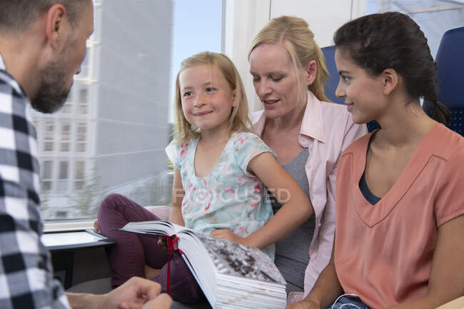 Семья путешествует на поезде, дочери читают книгу — стоковое фото