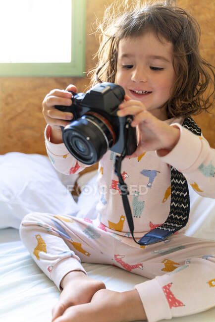 Мила дівчинка в піжамі в ліжку з камерою. — стокове фото