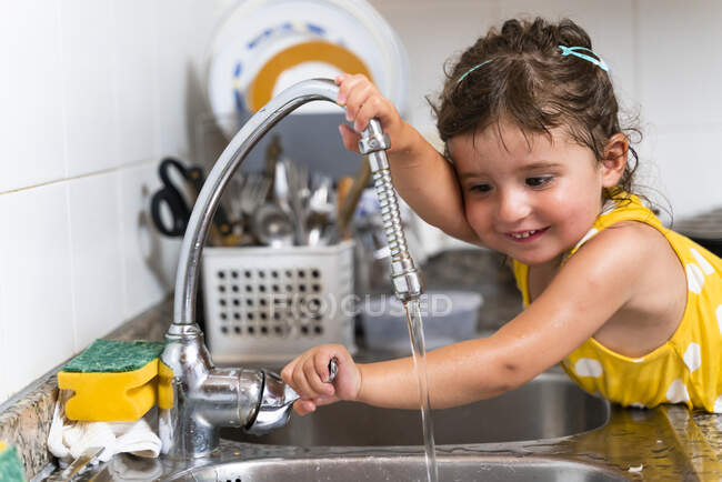 Kleines Mädchen spielt zu Hause in der Küche mit Wasser — Stockfoto