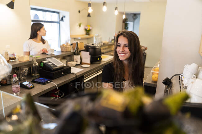 Lächelnde junge Frau hinter dem Tresen in einem Café — Stockfoto
