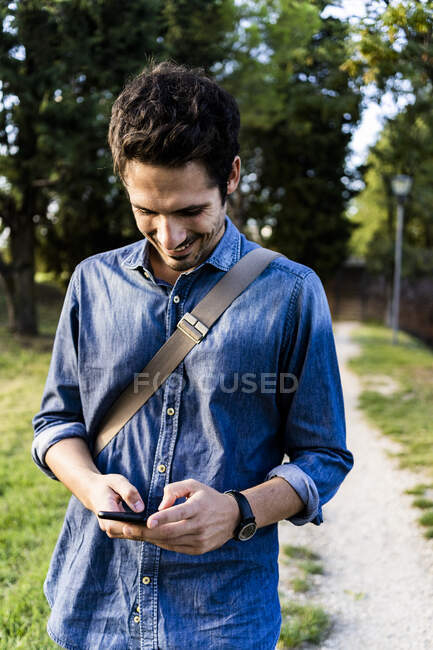 Homme souriant utilisant son smartphone — Photo de stock