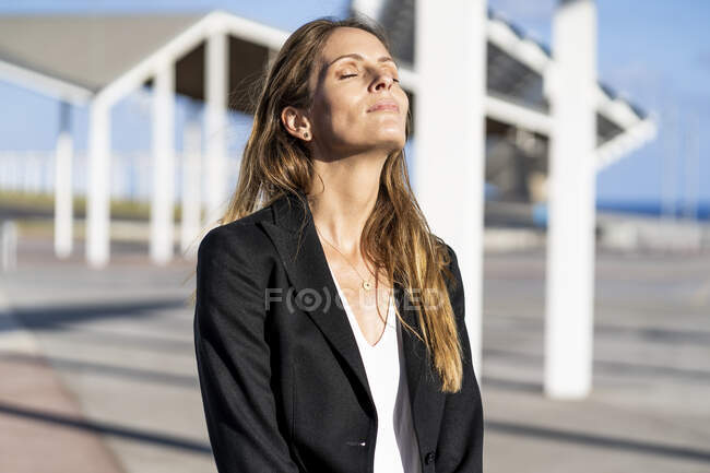 Donna d'affari in piedi all'aperto godendo il sole — Foto stock