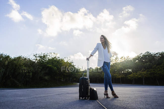 Businesswoman with baggage standing on a remote road — Stock Photo