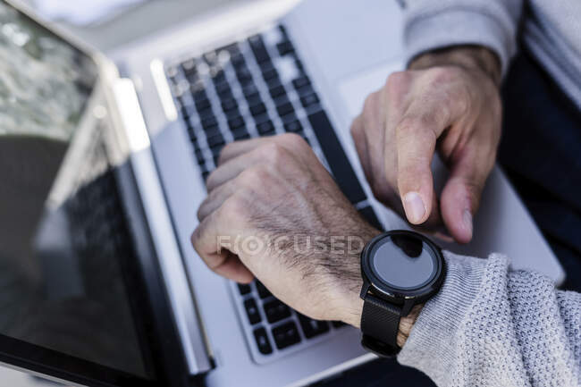 Close-up of man with smartwatch and laptop — Stock Photo