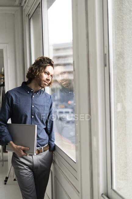 Mann hält Ordner im Atelier und schaut aus dem Fenster — Stockfoto