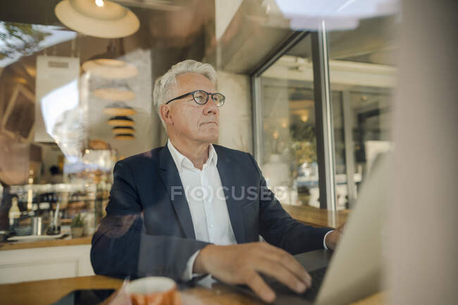 Senior businessman using laptop in a cafe — Stock Photo
