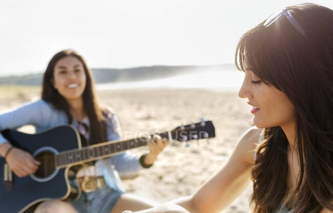 Dos mujeres con guitarra en la playa - foto de stock