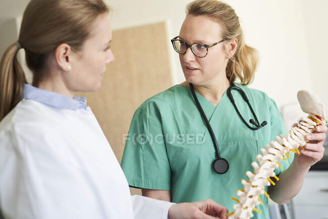 Жіночий лікар і жінка в наручниках з моделлю розмови про хребет — стокове фото