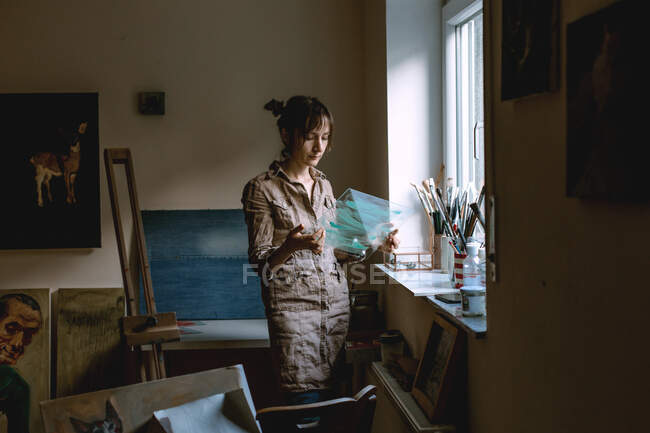 Artista femenina sosteniendo cristal en su estudio - foto de stock