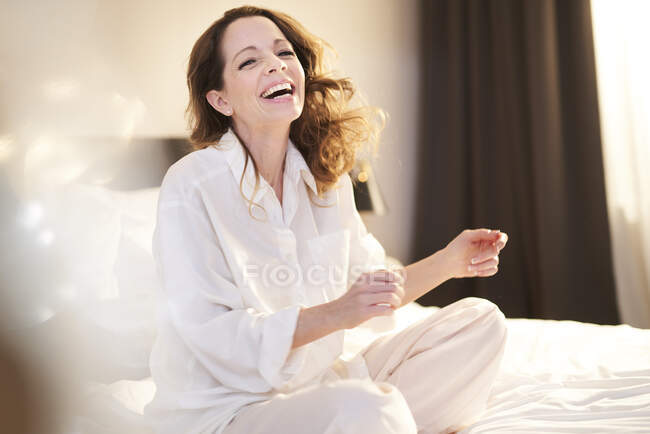 Laughing woman sitting on bed — Stock Photo