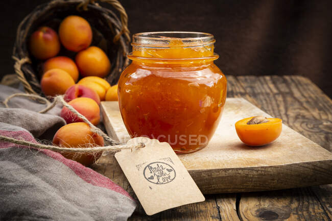 Apricot jam and apricots, sign 'made with love' on dark wood — Stock Photo