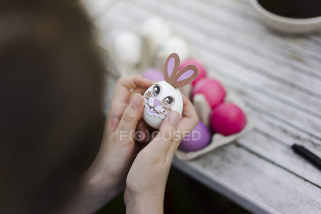 Close-up of girl decorating Easter egg on garden table — Stock Photo