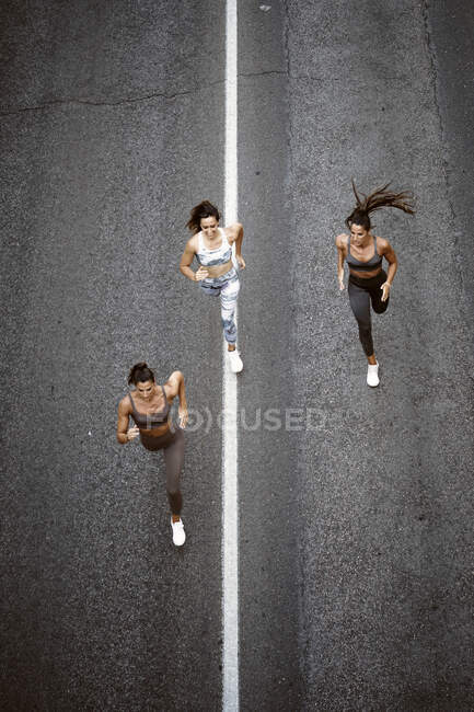 Top view of three sporty young women running on a street — Stock Photo