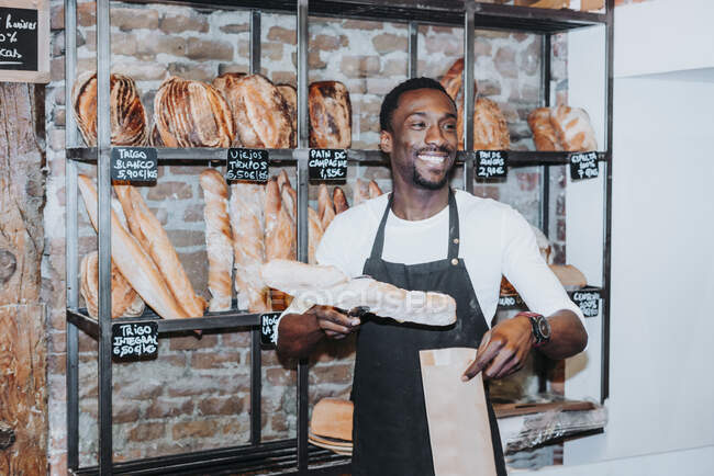 Homme souriant travaillant dans une boulangerie sur fond, gros plan — Photo de stock