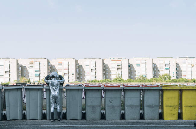 Rear view of boy dressed as an astronaut at garbage cans in the city — Stock Photo