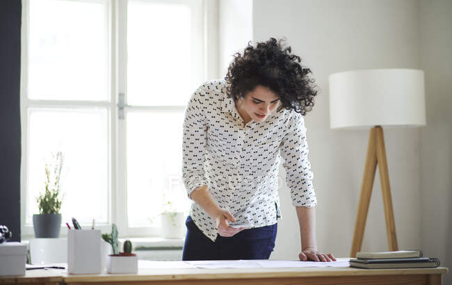 Young woman studying a plan on desk in office — Stock Photo