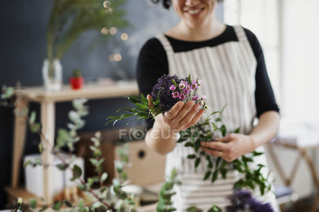 Gros plan d'une femme tenant des fleurs dans un petit magasin — Photo de stock