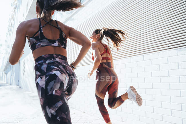 Вид сзади на двух спортсменок, бегающих в городе — стоковое фото