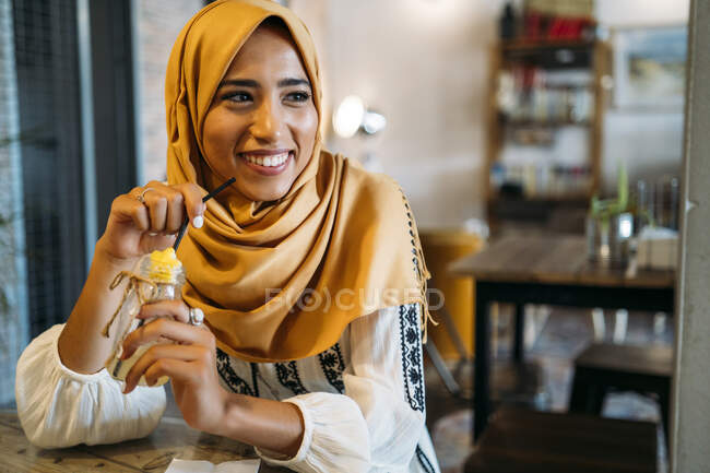 Молода муслімна жінка у жовтому хіджабі в кафе. — стокове фото