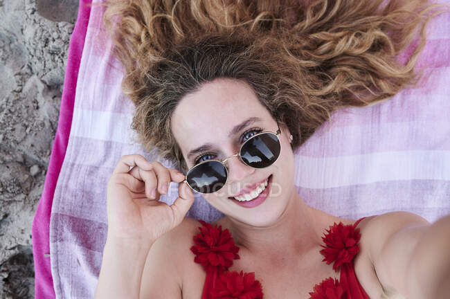 Auto-retrato de sorrir jovem deitado na toalha na praia — Fotografia de Stock